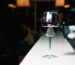 A glass of red wine close-up on a bar, white counter. Dark background.